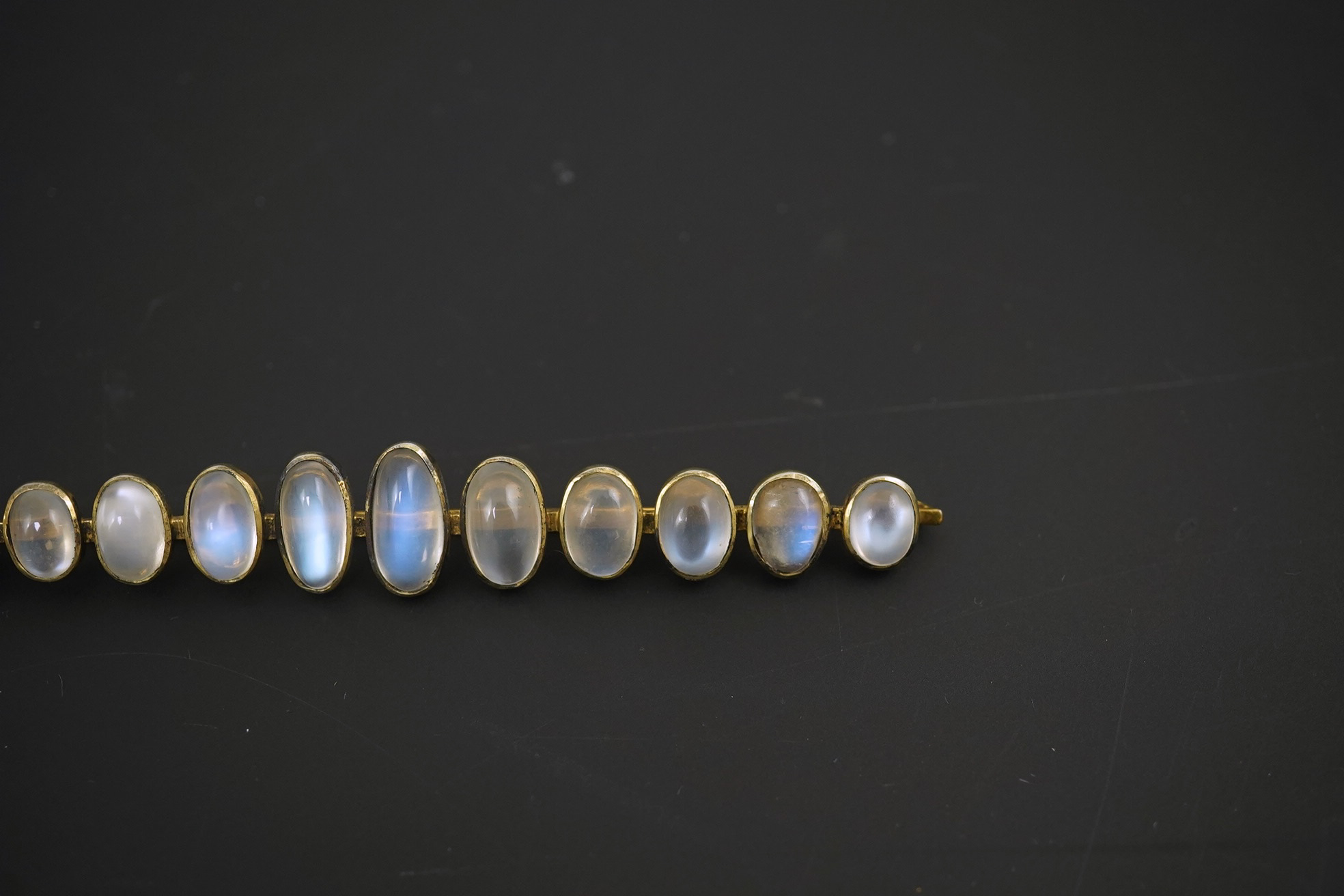 A gold and eleven stone graduated cabochon moonstone set bar brooch